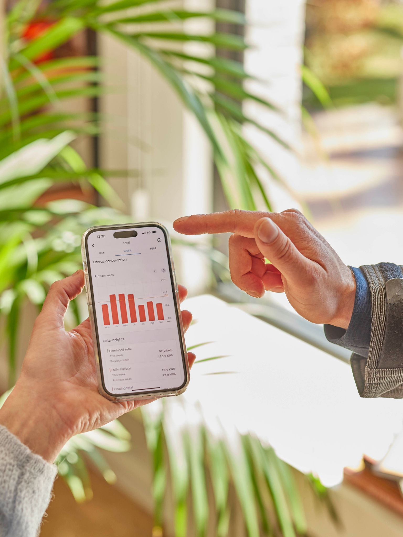 Deux personnes consultent ensemble les données de performance d'une pompe à chaleur sur une application mobile