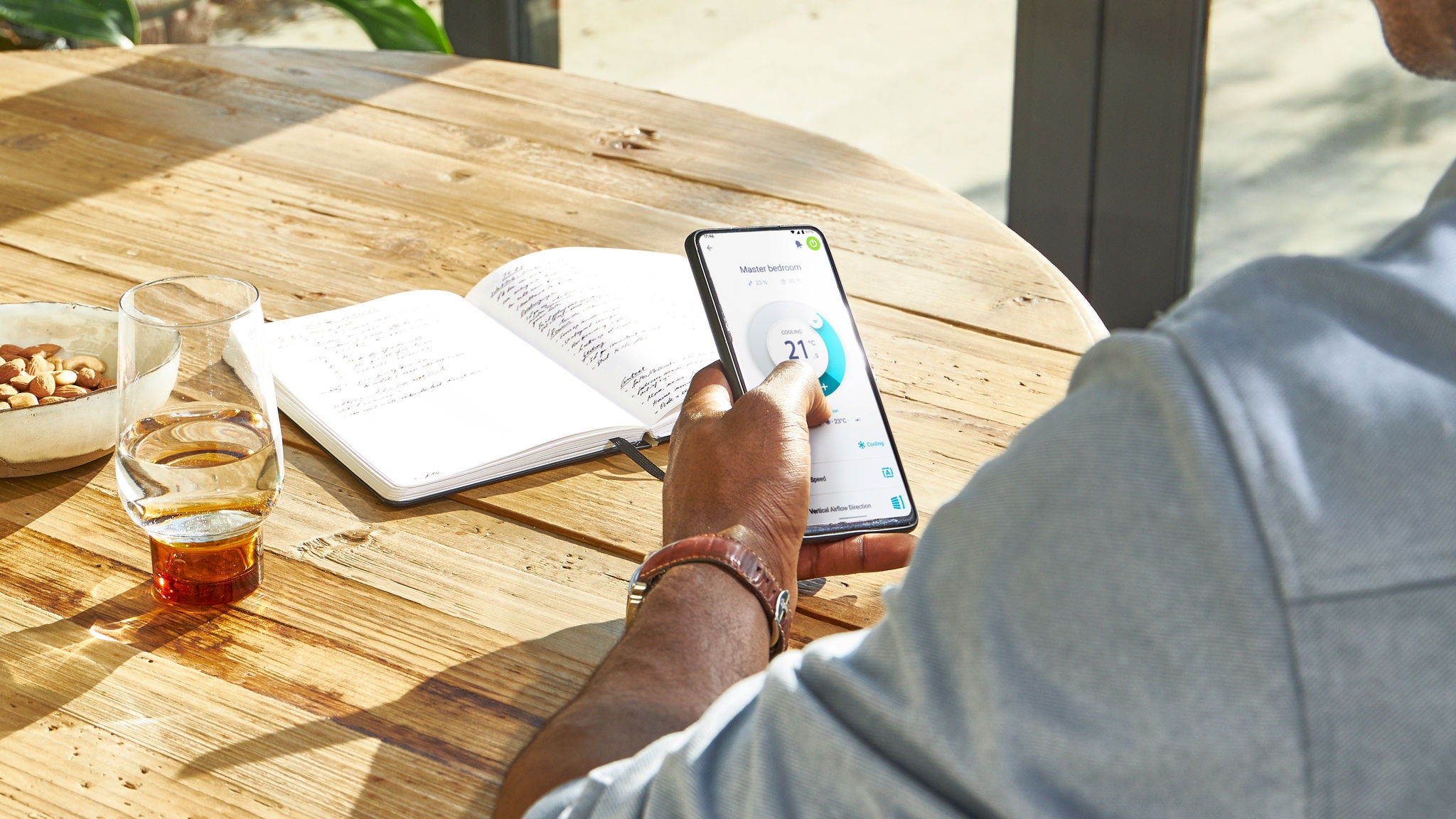 Homme régulant la température dans sa maison depuis tout lieu en utilisant l’application Onecta sur un smartphone