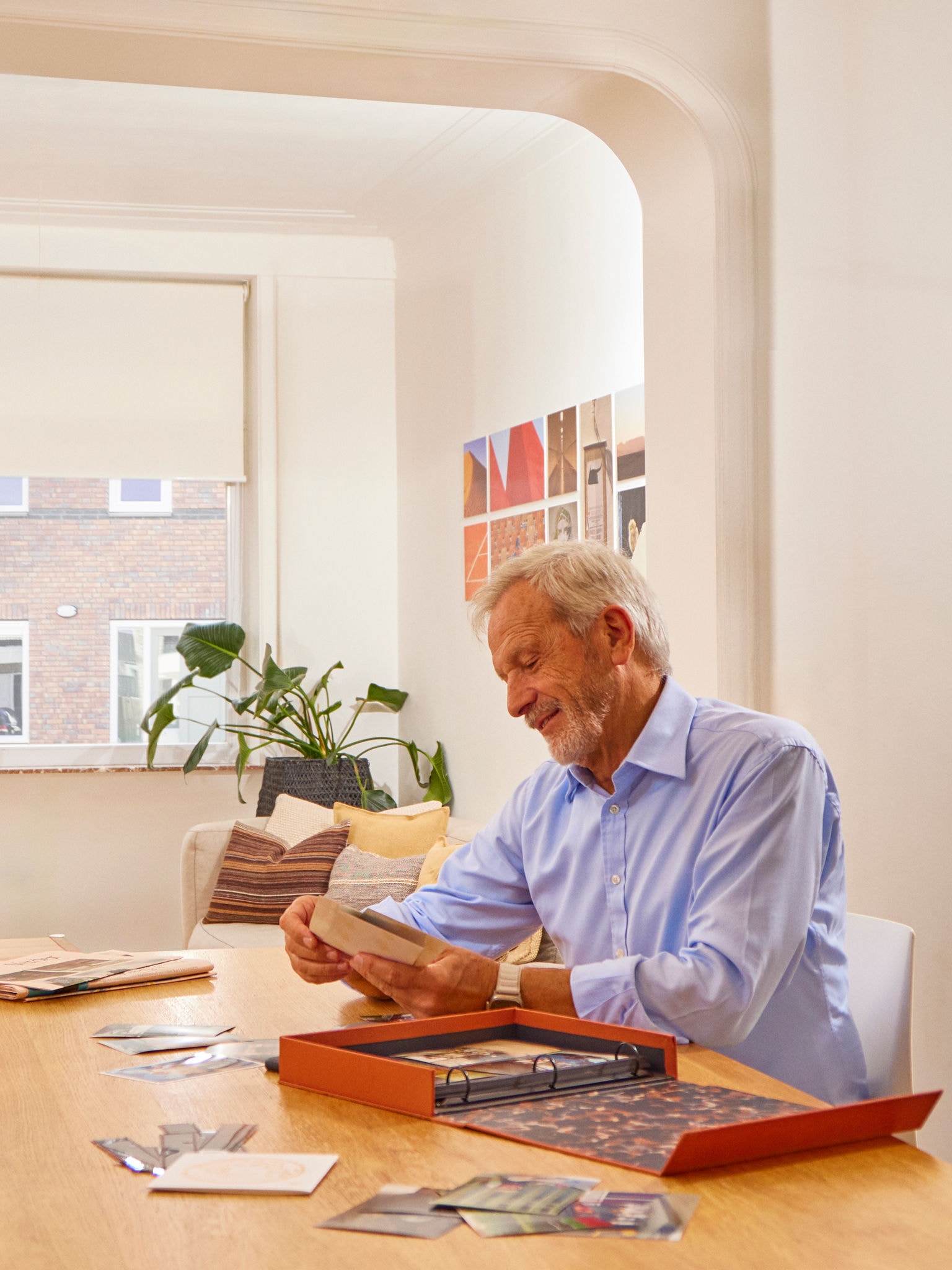 Homme assis à une table avec un album photo dans un salon sec et sain grâce à une ventilation régulant l'humidité