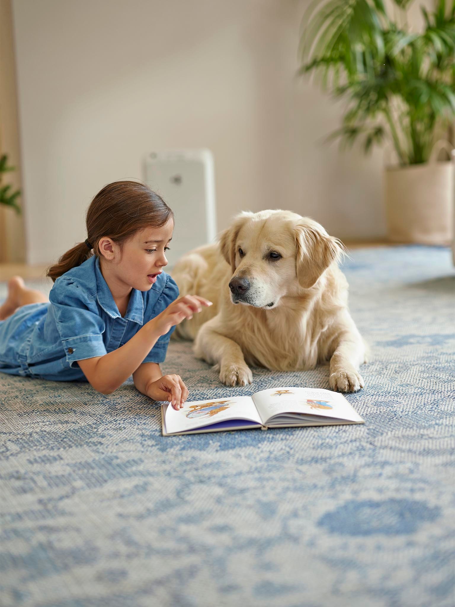 Fille allongée par terre à côté d’un chien pendant que le purificateur d'air purifie l’air