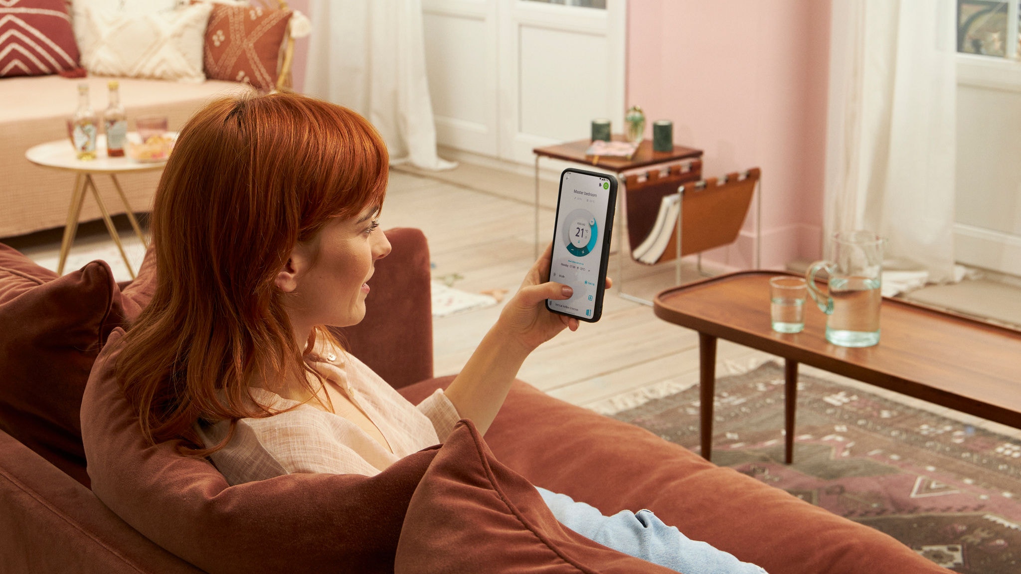 Femme assise sur un canapé à la maison, utilisant l'application Onecta sur son téléphone portable