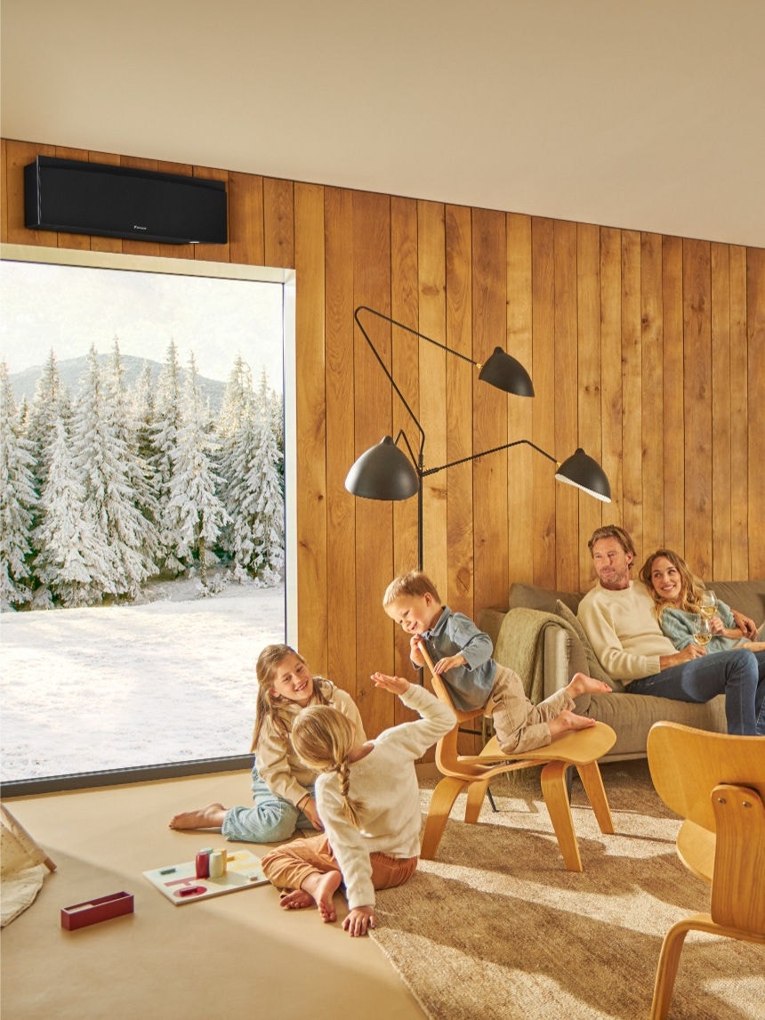 Famille profitant d'un air intérieur pur grâce au purificateur d'air Daikin, les enfants jouant aux échecs et les adultes se détendant en buvant des boissons dans un salon lumineux et bien ventilé.
