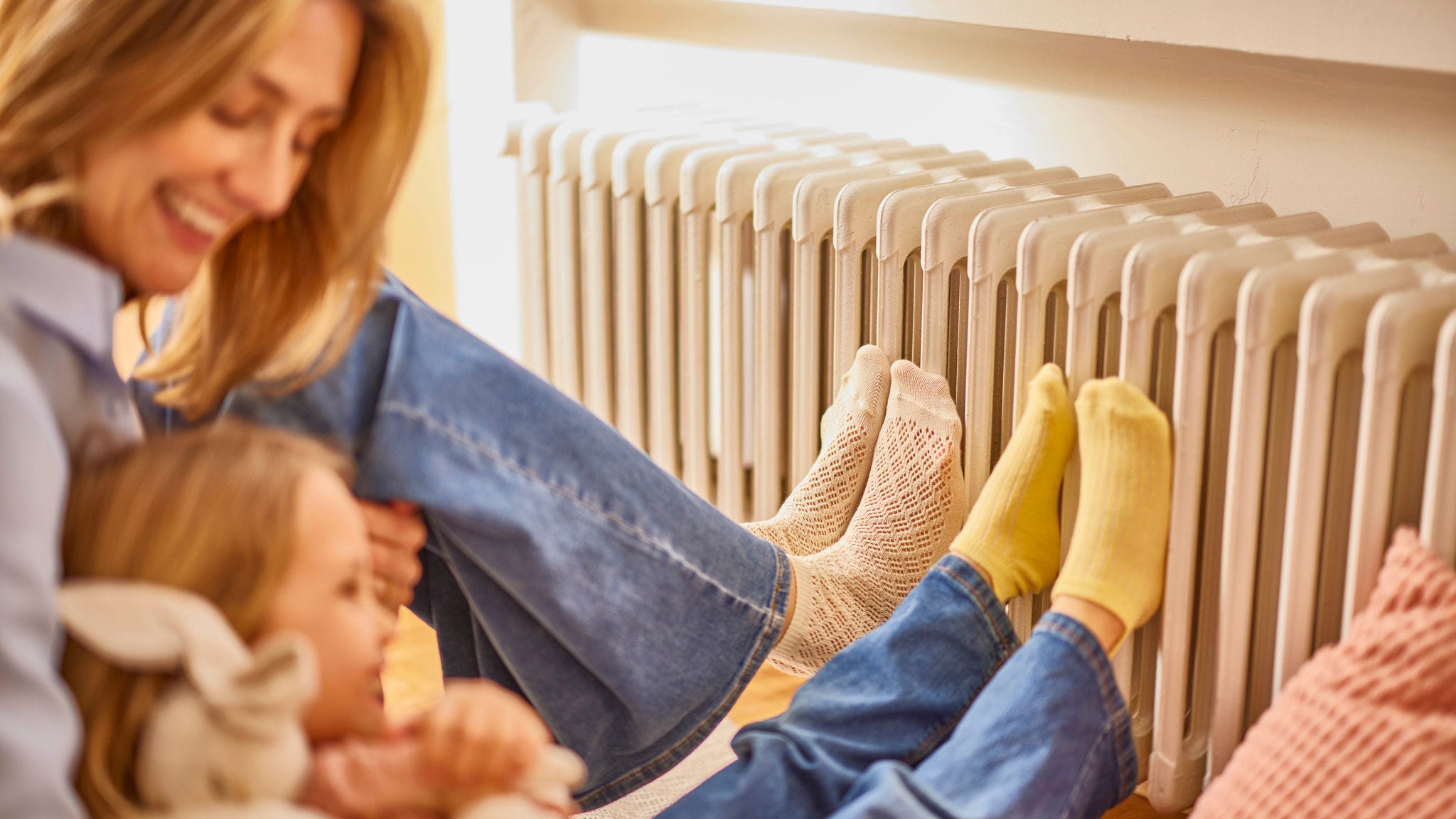 Mère et fille se réchauffant les pieds sur un radiateur dans une maison chaleureuse et confortable