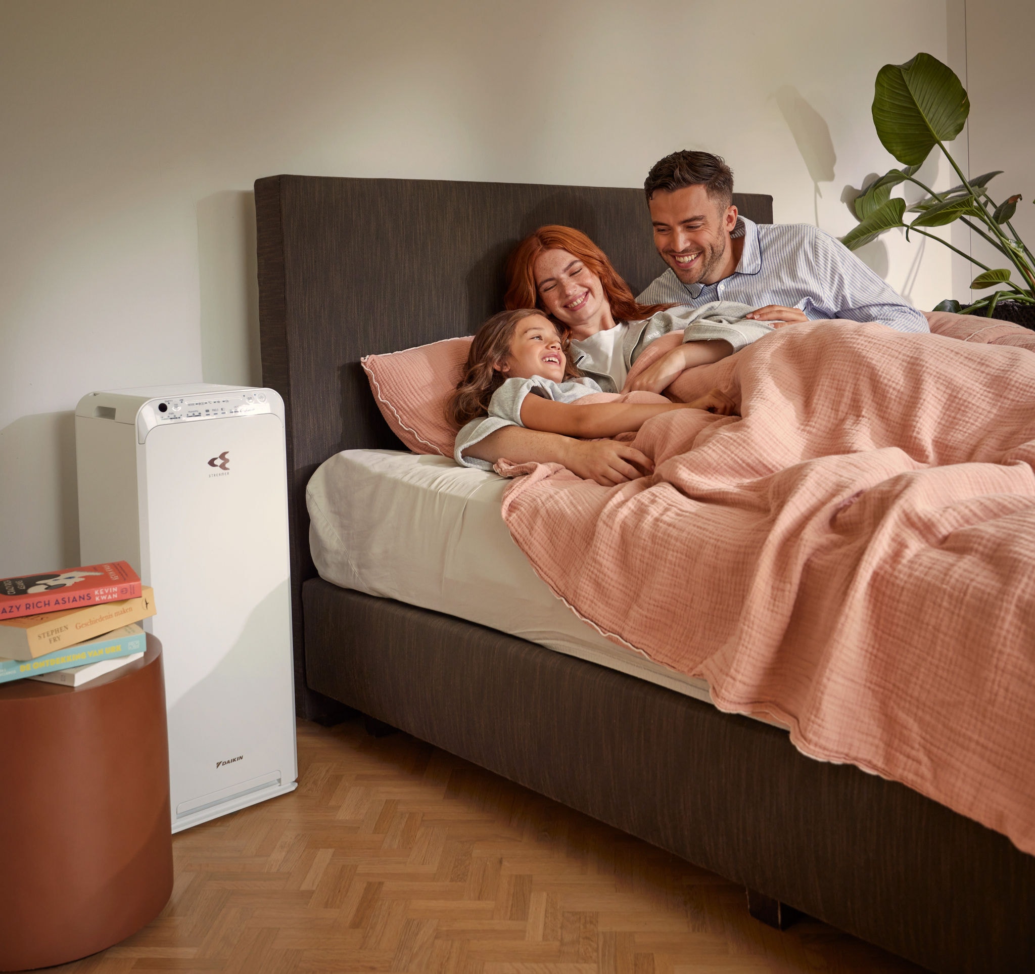 Couple avec enfant se relaxant dans une chambre et profitant d’un air pur généré par un purificateur d'air