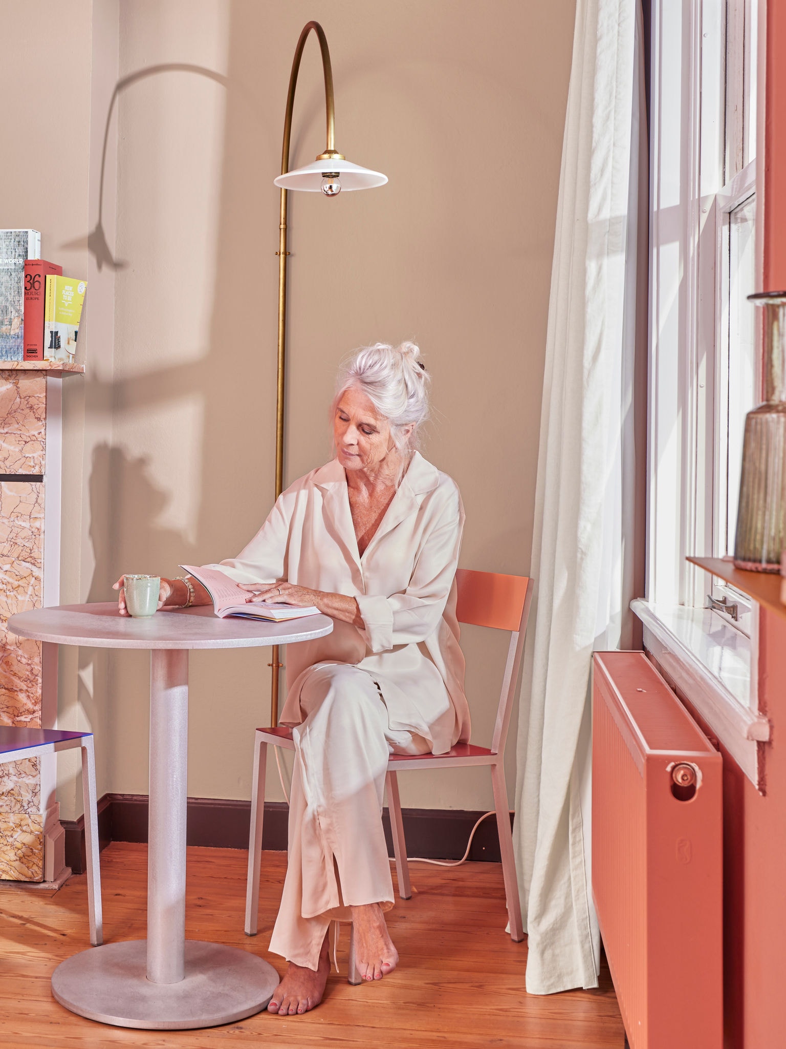 Femme lisant à table près d'un radiateur connecté à un système de chauffage de type pompe à chaleur