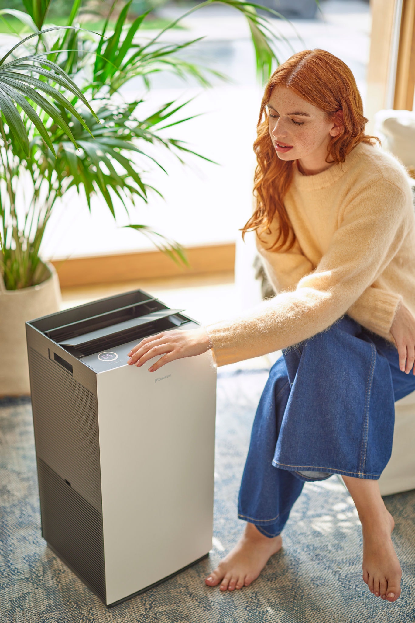 Femme se détendant dans un fauteuil et utilisant un purificateur d'air pour l'obtention d’un air intérieur plus propre