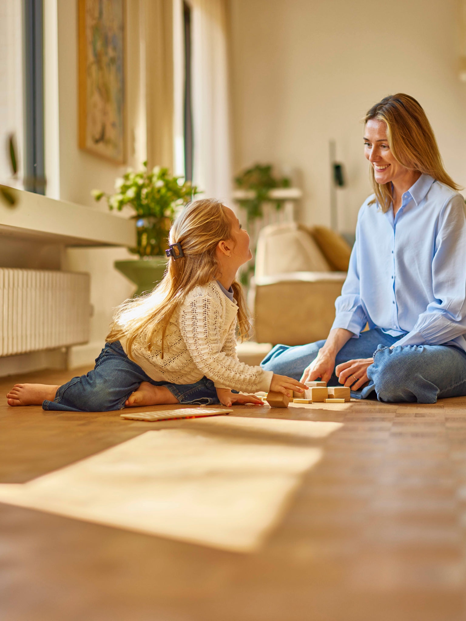 Mère jouant avec sa fille dans une pièce confortablement chauffée avec un radiateur mural