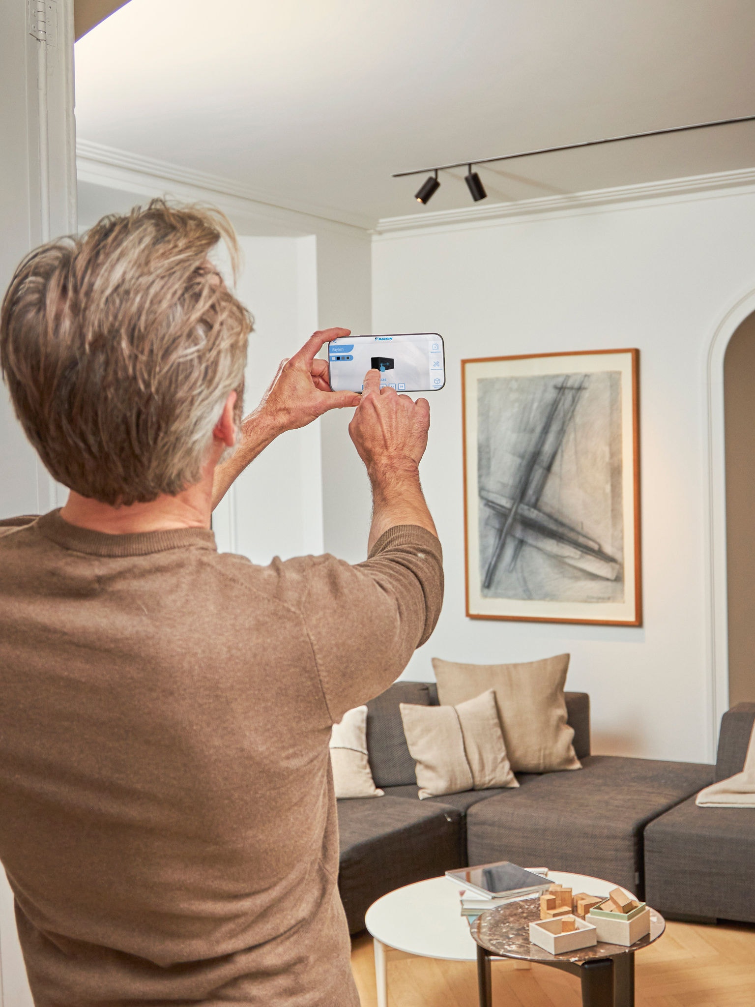 Homme utilisant l'application 3D avec des pompes à chaleur air-air à réalité augmentée pour visualiser les unités avec le design intérieur et extérieur
