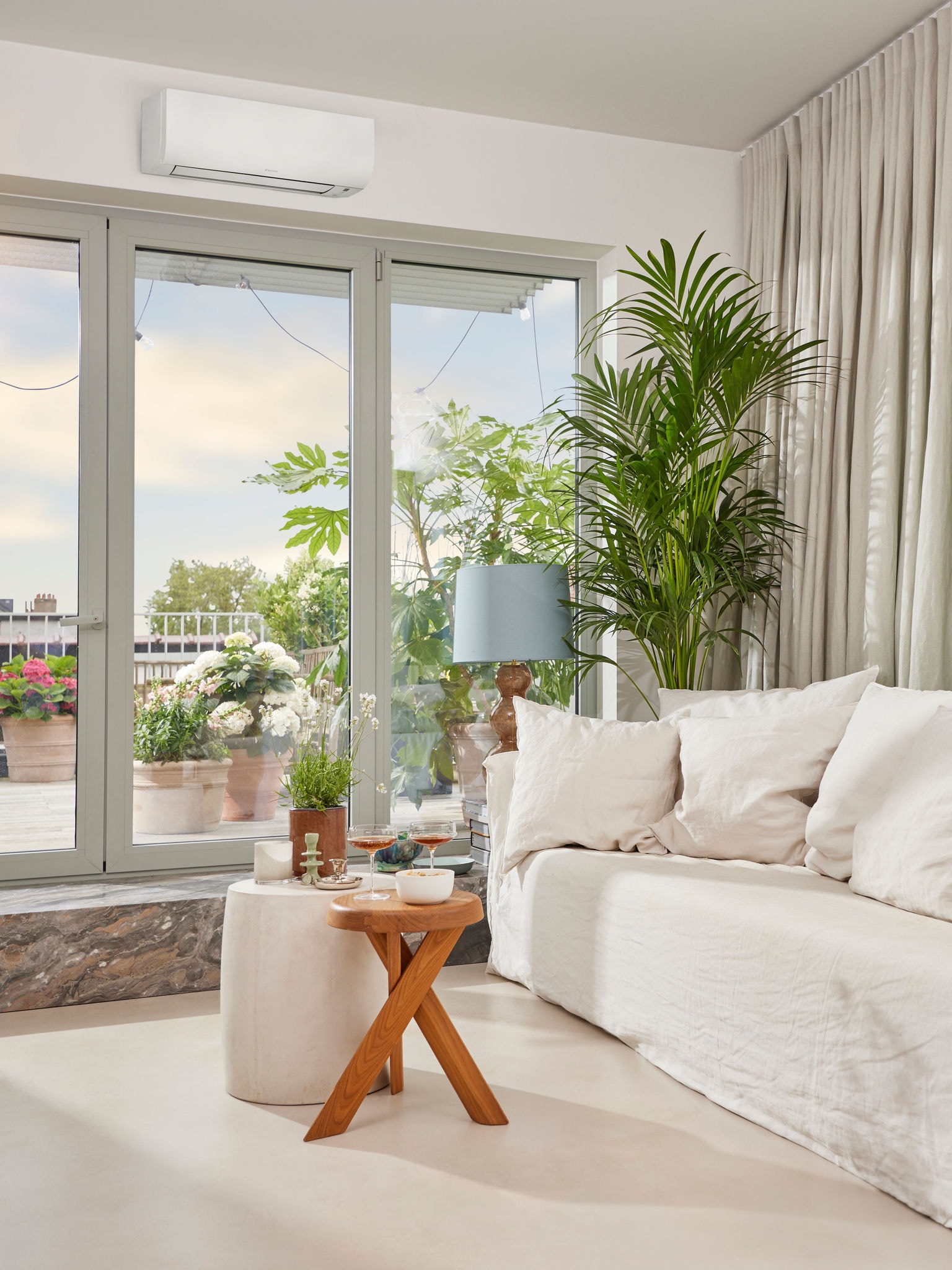 Salon lumineux et chaleureux avec un aménagement pour l'apéritif, de grandes portes vitrées donnant sur la terrasse avec un climatiseur installé au-dessus.