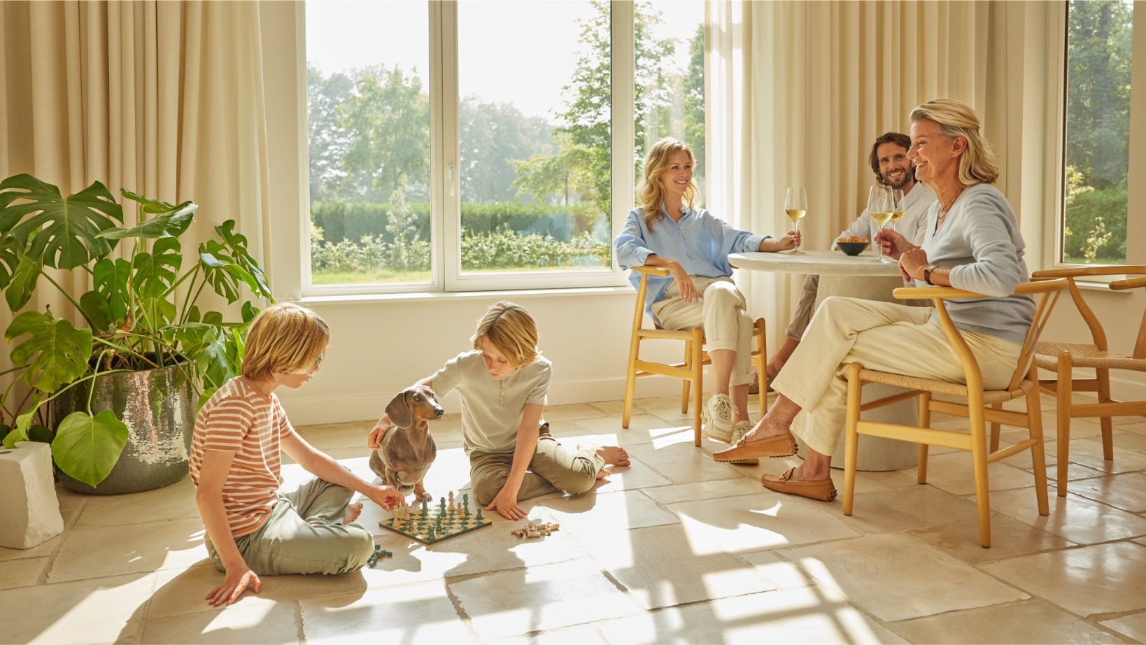 Famille profitant d'un air intérieur pur grâce au purificateur d'air Daikin, les enfants jouant aux échecs et les adultes se détendant en buvant des boissons dans un salon lumineux et bien ventilé