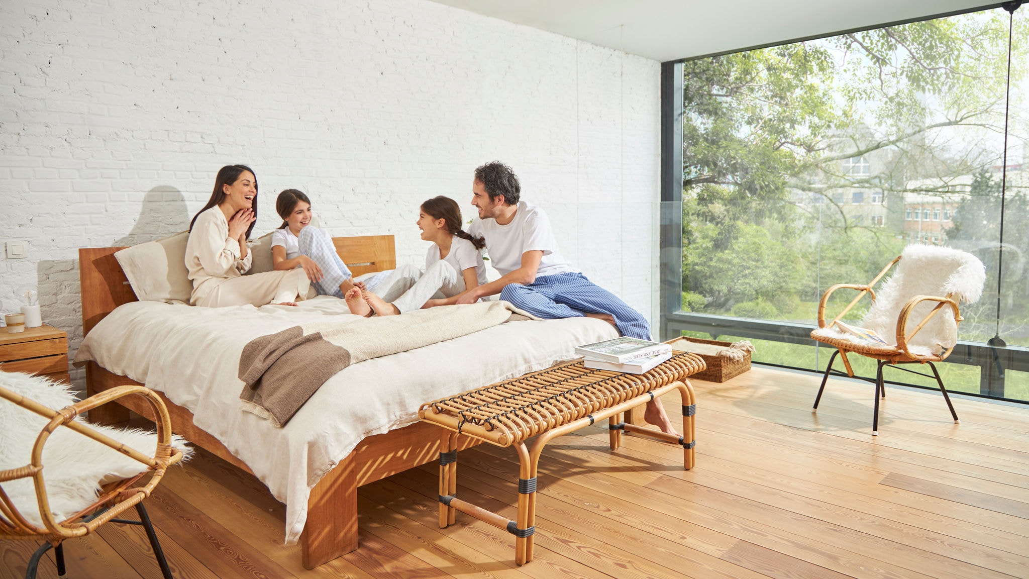 Famille discutant sur un lit dans une chambre avec une grande paroi vitrée, bénéficiant d'une bonne qualité de l'air intérieur et d'une lumière naturelle abondante