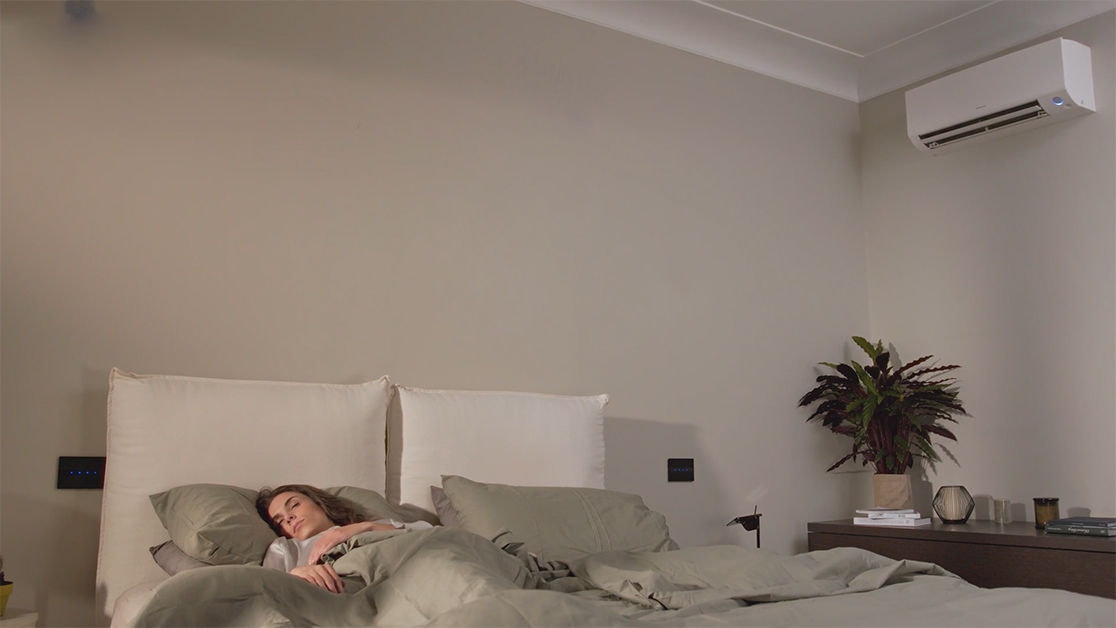 Femme dormant paisiblement avec son unité Daikin en mode nuit silencieuse