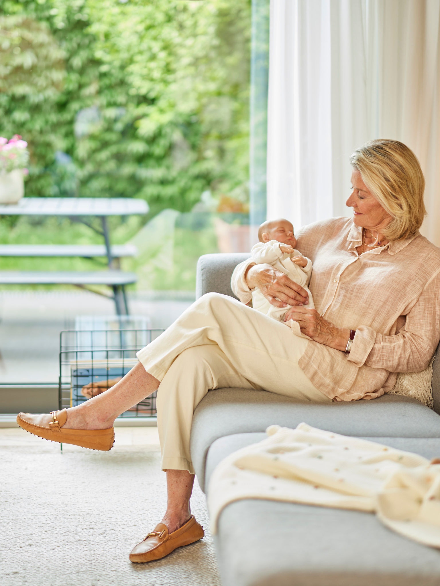 Femme tenant un bébé, assise sur un canapé dans une pièce confortablement chauffée.