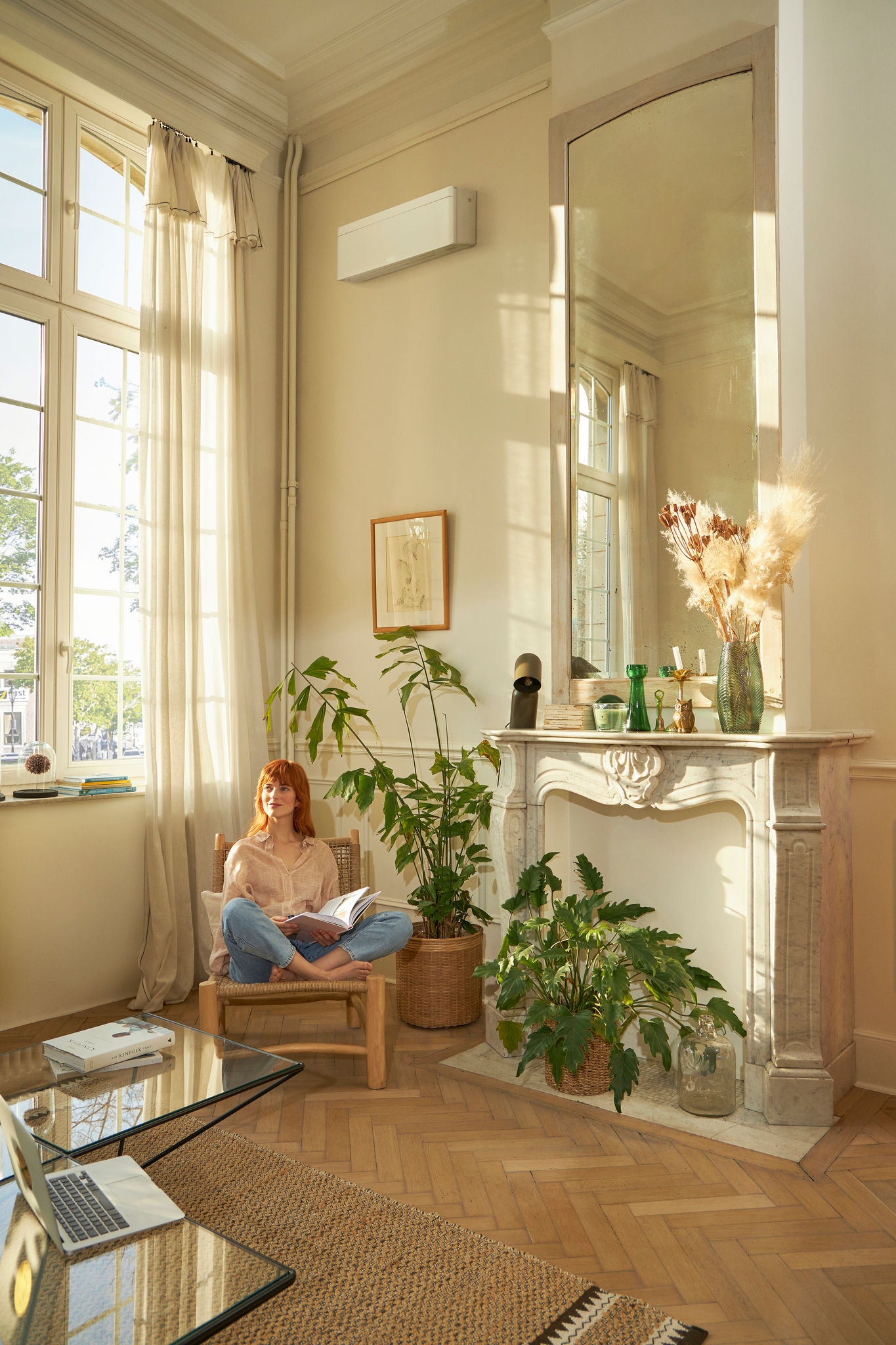 Femme lisant un magazine dans une pièce remplie de plantes avec un climatiseur Inverter