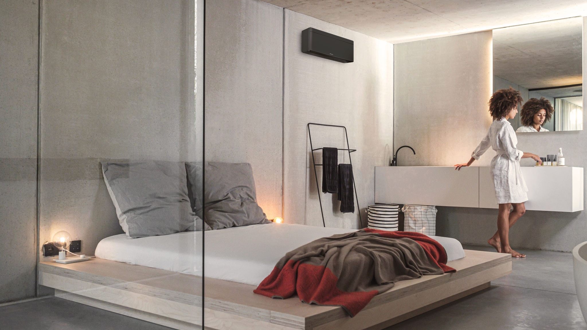 Une femme se préparant pour la journée dans sa chambre à coucher et sa salle de bains intégrée, climatisées et chauffées par une unité intérieure Stylish.