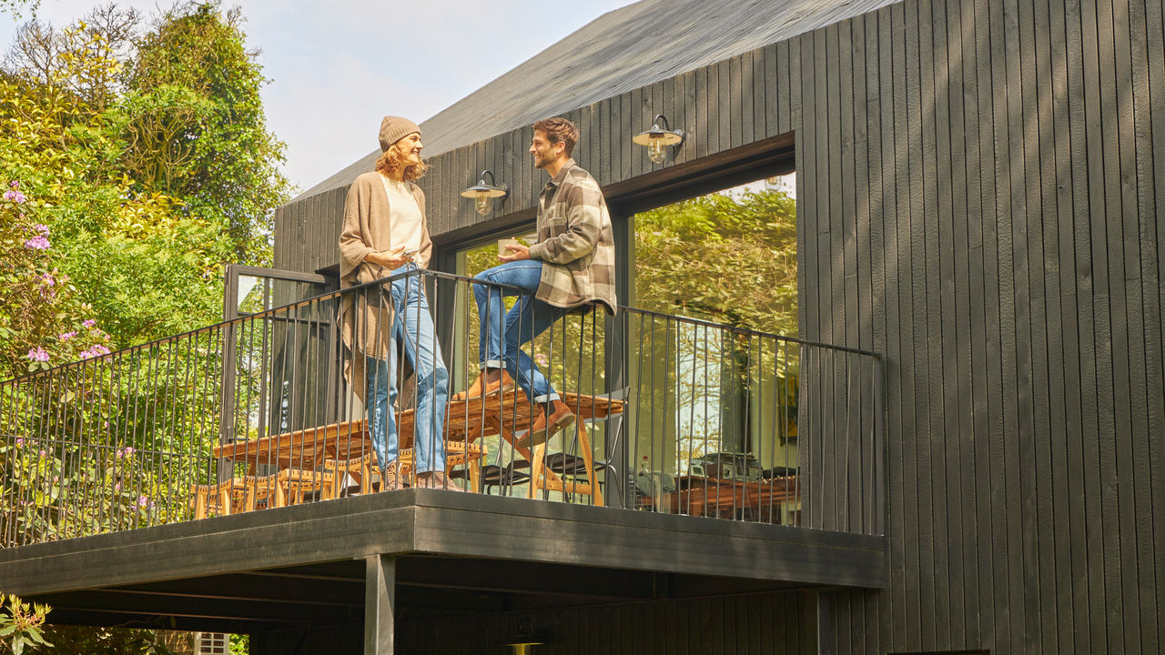 Couple discutant sur la terrasse d’un bungalow au milieu de la nature